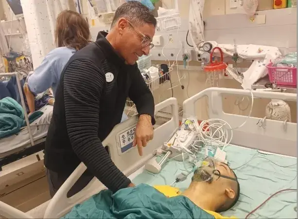 Dr. Amir Kershenovich speaking to a young patient in recovery room after surgery